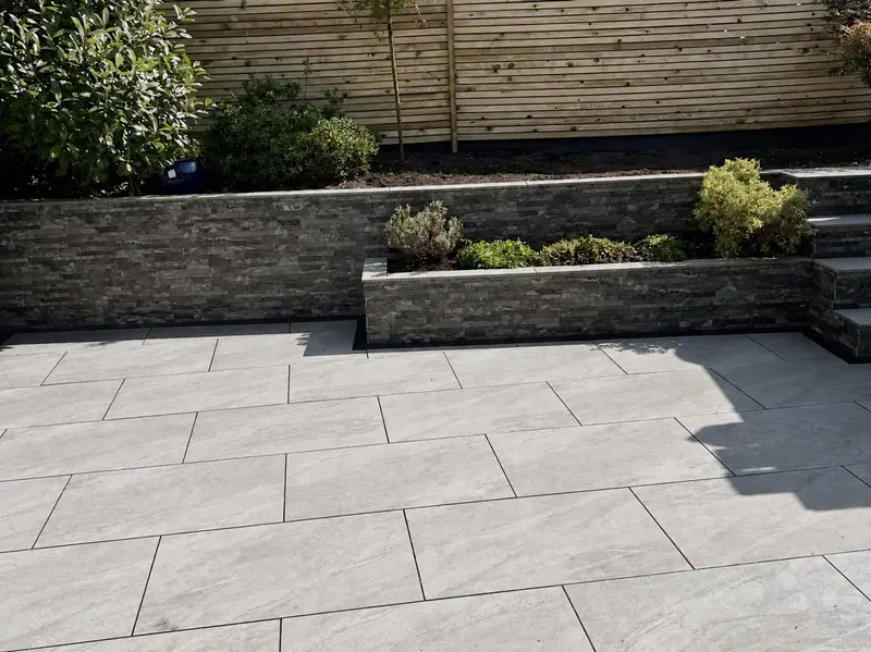 Grey porcelain paving beside raised stone planters and slatted screening