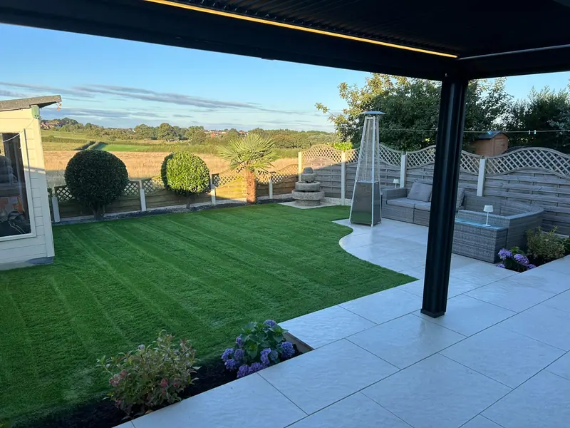 Finished garden with striped artificial lawn, porcelain patio, pergola and landscaped planting