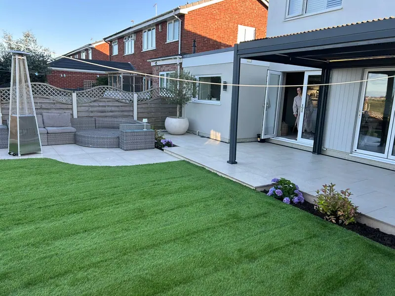 Landscaped garden with porcelain patio, covered pergola, artificial lawn and planted borders