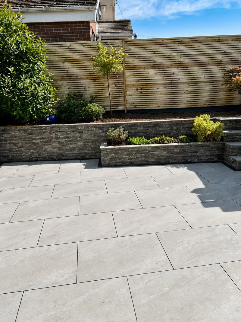 Grey porcelain patio with raised stone planters and slatted screening