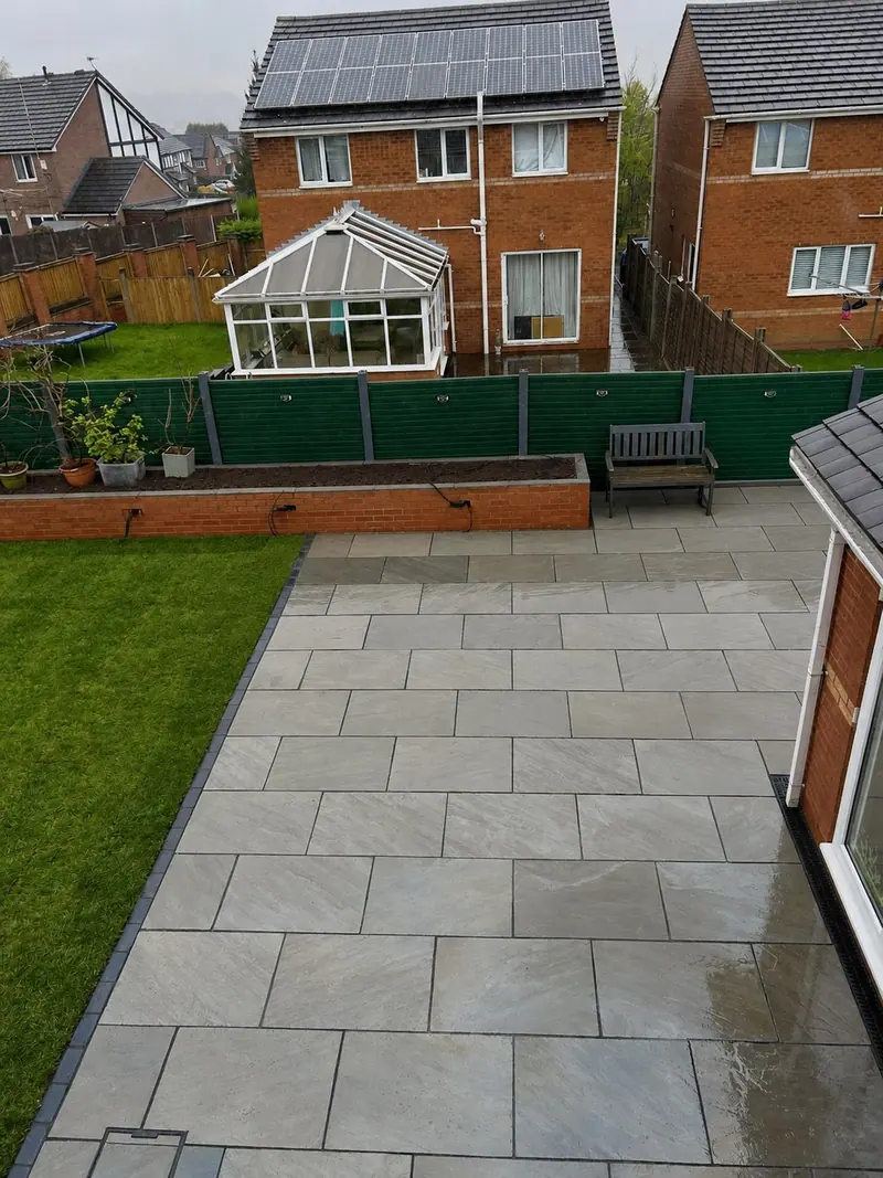 Grey paved patio, artificial lawn and raised brick planting bed