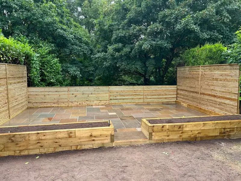Paved garden with slatted timber screening and raised sleeper beds